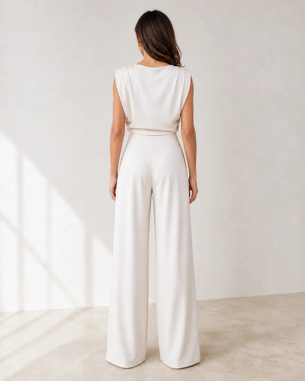 Women's white asymmetric draped top and wide-leg trousers set, rear view.